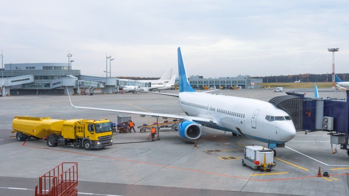 Passenger plane at the telescope of the airport terminal building, for maintenance and refueling before a new flight