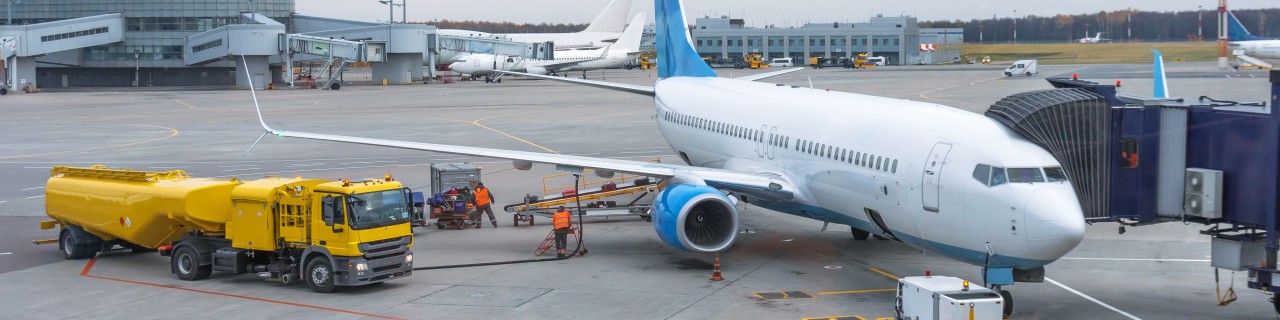 Passenger plane at the telescope of the airport terminal building, for maintenance and refueling before a new flight