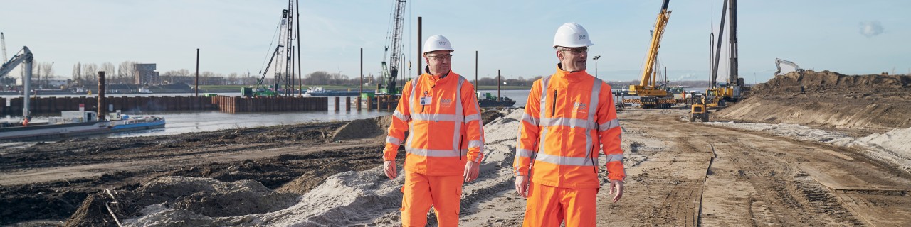 Baurbeiter in orangen Arbeitsanzügen auf Baustelle