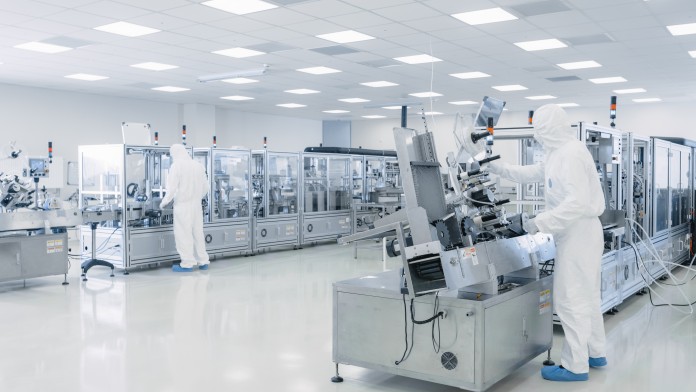 Moderne Produktionsstätte mit zwei Mitarbeitern in Reinraumanzügen