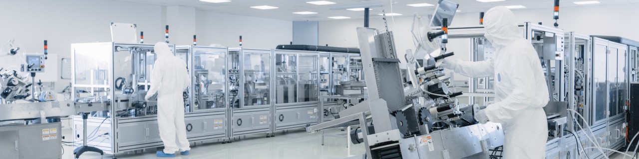 Modern production facility with two employees in cleanroom suits.