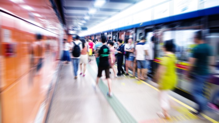 Personen auf Bahnsteig zwischen Zügen; Bild ist verschwommen