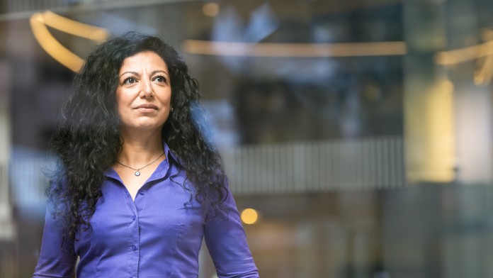 Frau mittleren Alters schaut durch ein Fenster in die Ferne