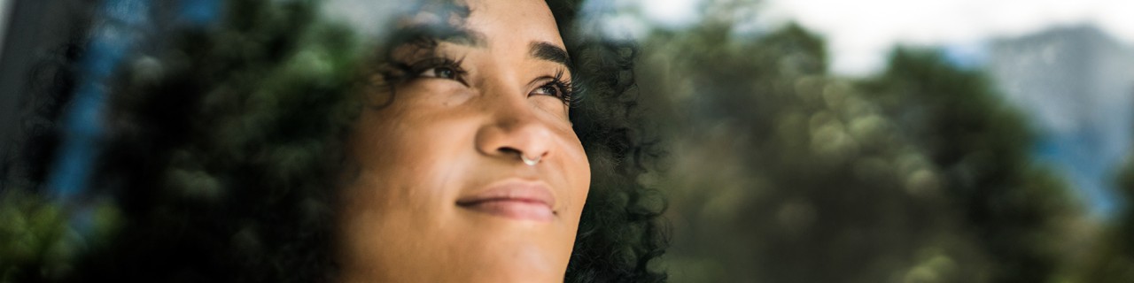 Young woman gazes into the distance from the window