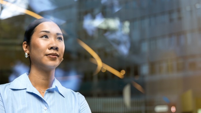 Junge Frau blickt durch ein Fenster in die Ferne