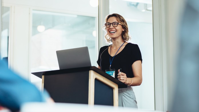 Geschäftsfrau steht am Podium mit Laptop