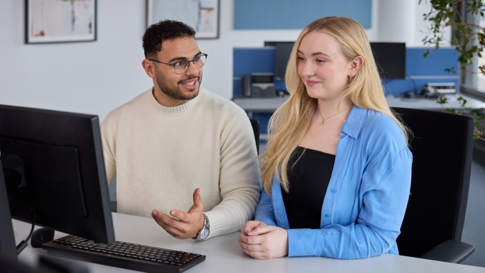 Zwei Werkstudierende arbeiten gemeinsam am Bildschirm