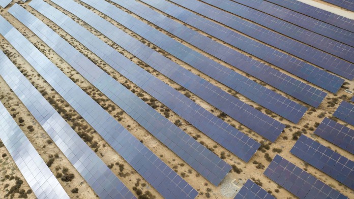 Drone aerial shooting of solar power farm raws of reflective panels. At cloudy day in Spain.