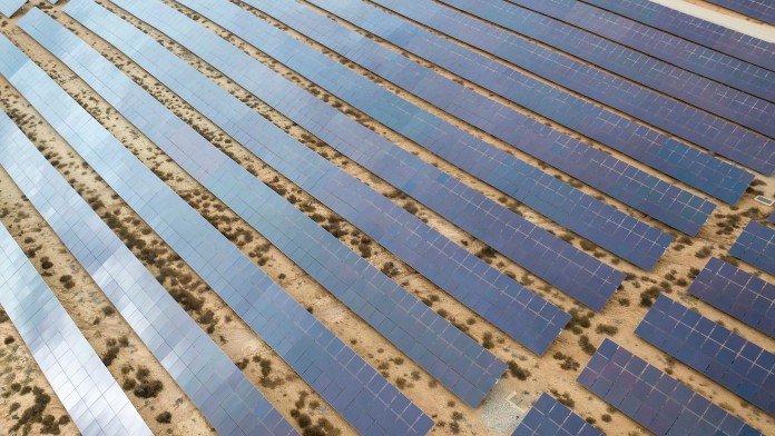 Drone aerial shooting of solar power farm raws of reflective panels. At cloudy day in Spain.