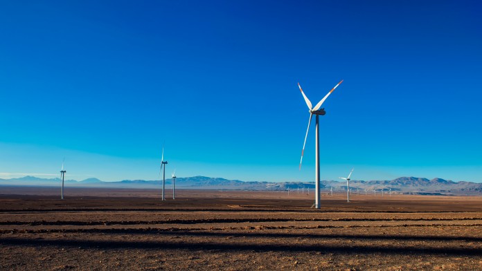 viele Windkaftanlagen an Land vor blauem Himmel