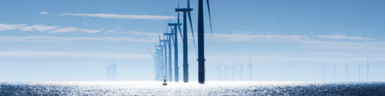 Windräder im Meer vor blauem Himmel