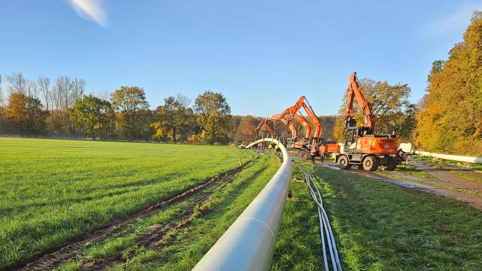 Rohrleitung im Vordergrund und Baumschinen im Hintergrund