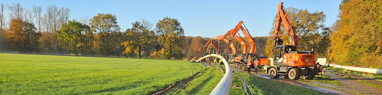 Rohrleitung im Vordergrund und Baumschinen im Hintergrund